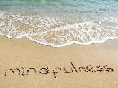 mindfulness carved in the sand on a beach