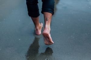 man's bare feet walking on wet sand