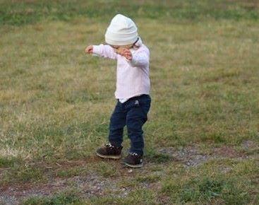 a little child walking looking at their feet hands held high