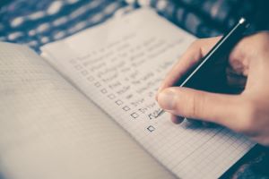 a hand writing a to do list in a notebook